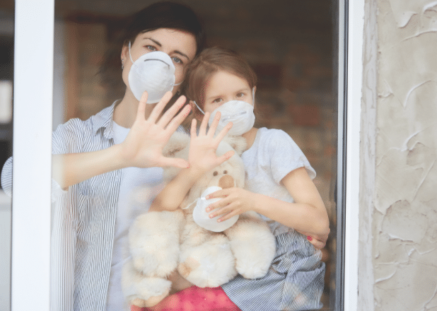 mom and daughter hands on window waving with masks on