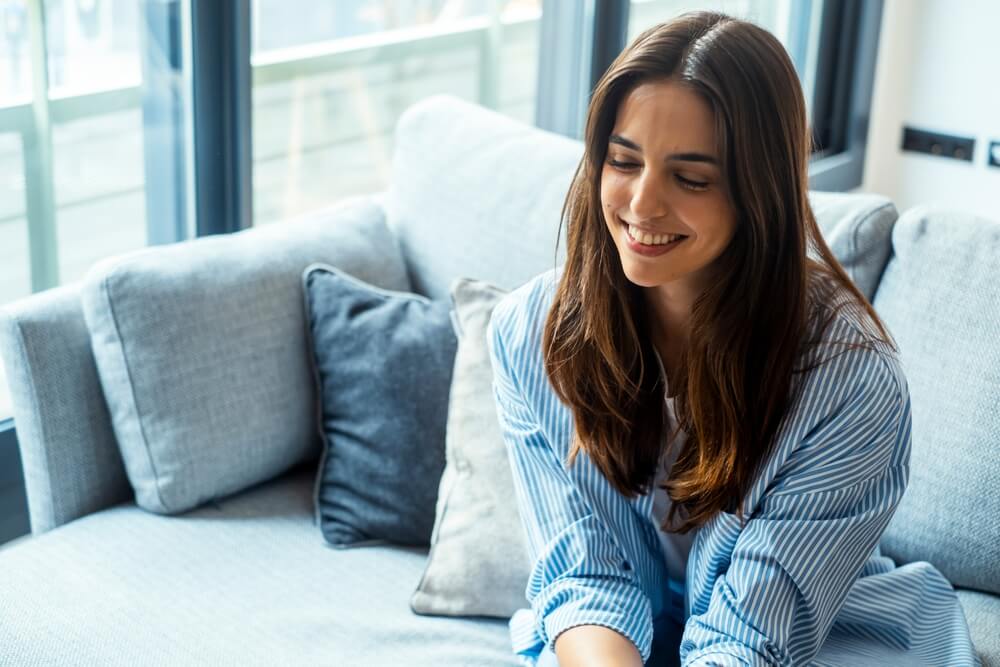 smiling_woman Young female sitting on sofa smiling during a therapy session