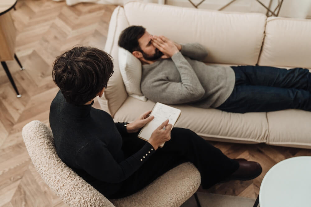 top-view-mature-female-psychologist-eyeglasses A therapist and a patient working through suicidal ideation treatment therapy.