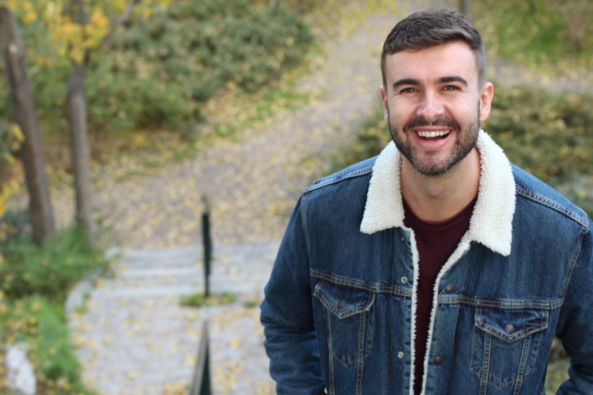 young-man-smiling Young man smiling outside while surrounded by nature