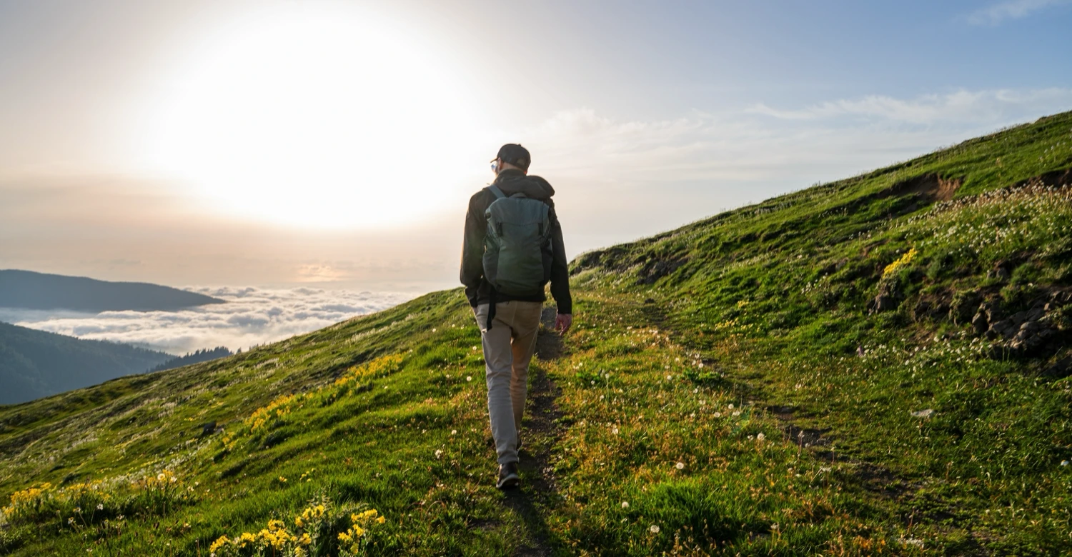 A person climbing up a hill on a bright sunny day A person climbing up a hill on a bright sunny day