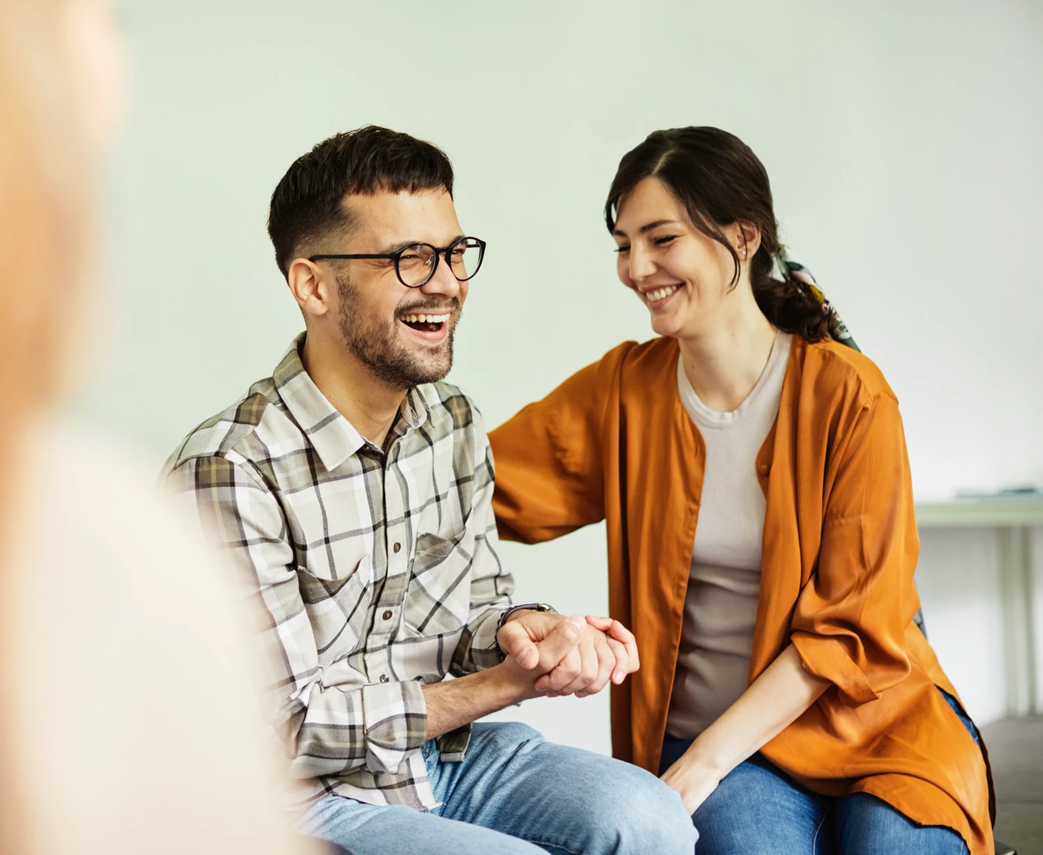 A young adult male and female laughing together during a group therapy session A young adult male and female laughing together during a group therapy session