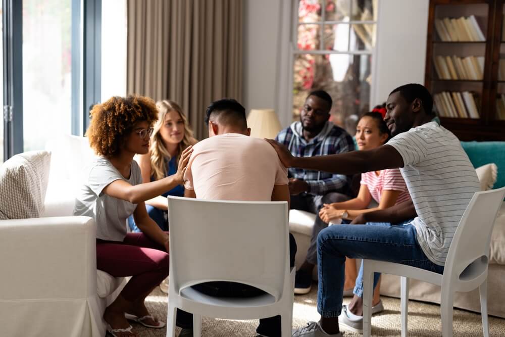  Group therapy session where participants are listening and comforting each other